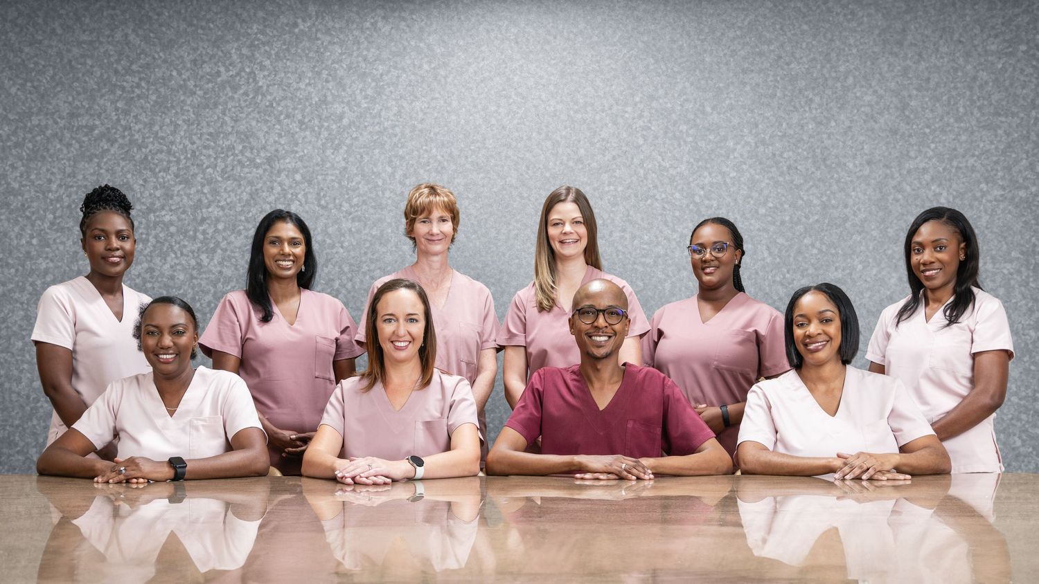 Diverse medical team of women in pink and white scrubs posing together for a professional group photo.