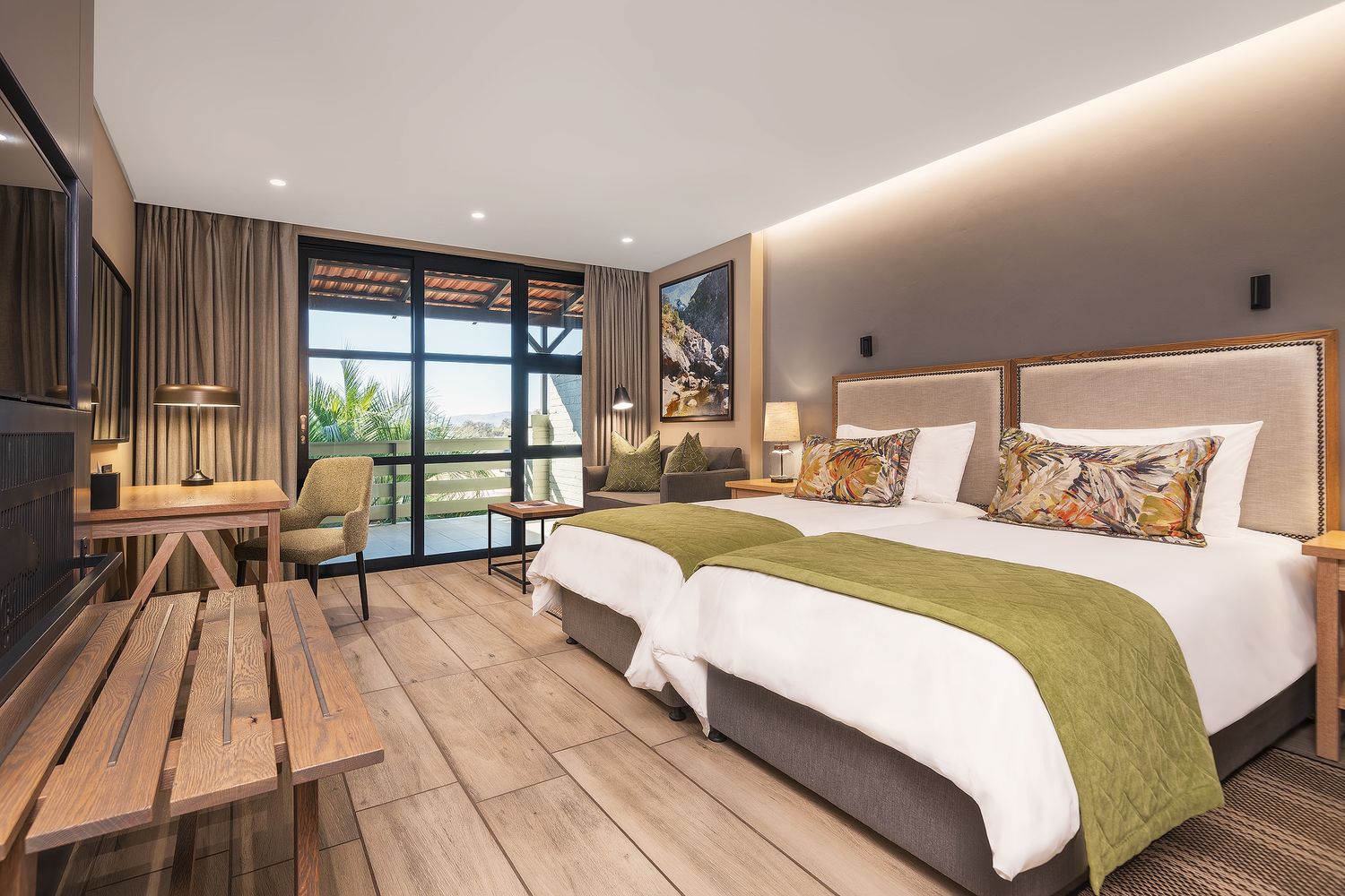 Elegant twin bedroom with green bedding, wooden floors, and large windows overlooking a lush garden at a safari lodge.