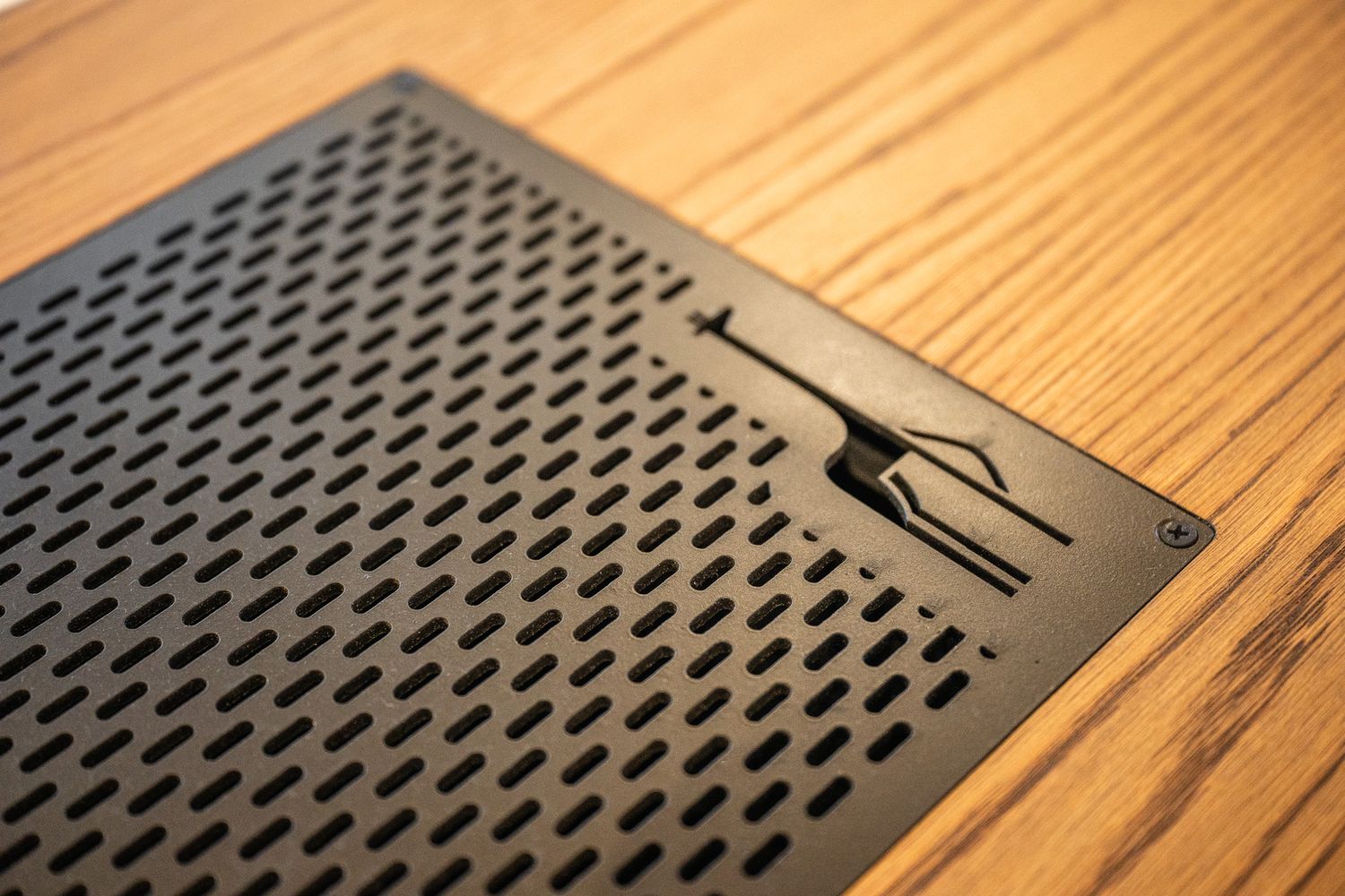 Close-up of decorative black metal giraffe cutout on perforated wood panel surface.