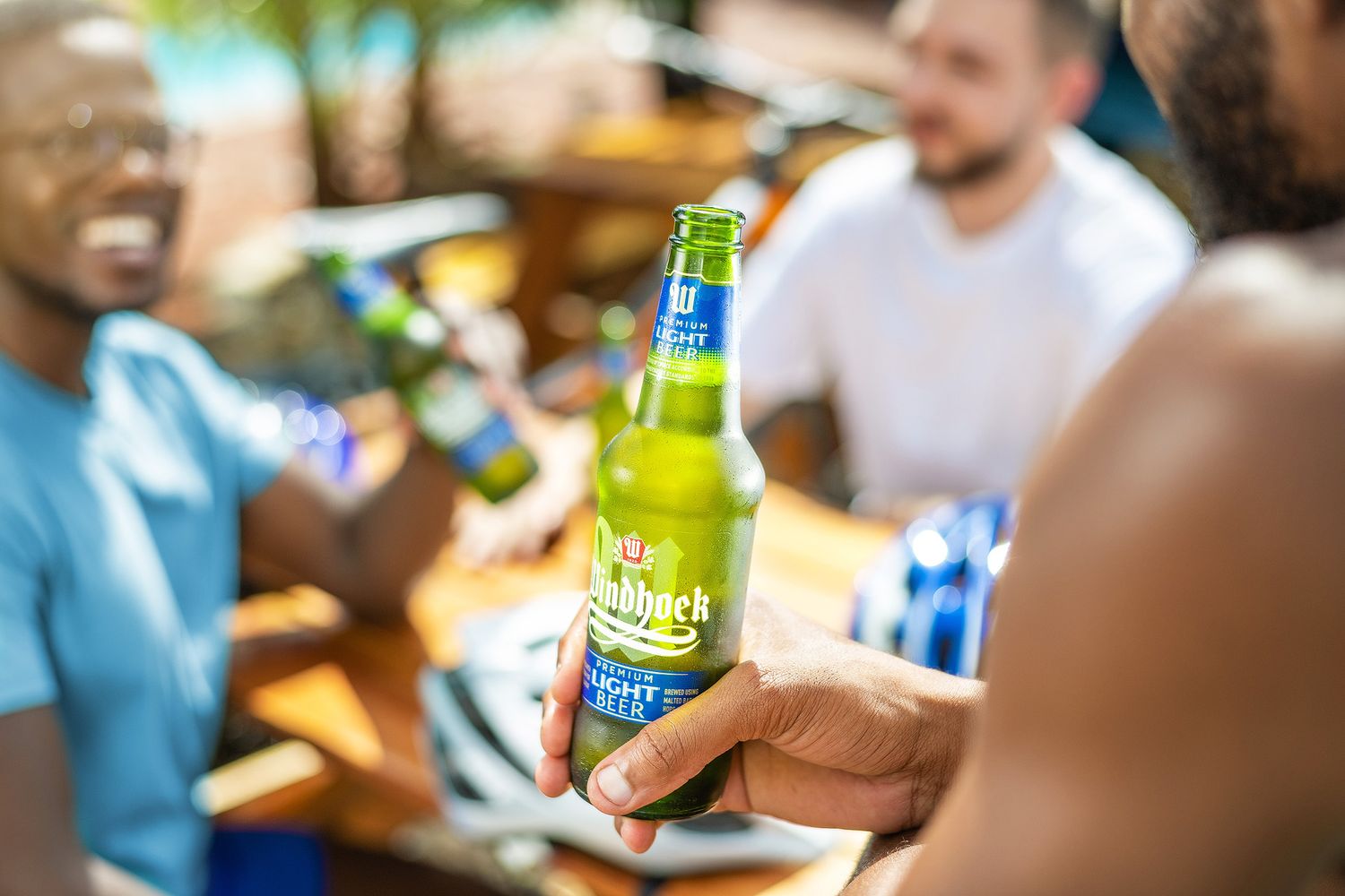 Friends enjoying cold Desperados beer bottles outdoors at a sunny social gathering.