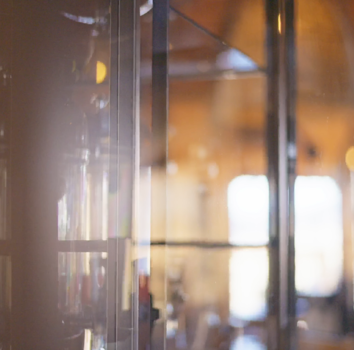Close-up of a glass display cabinet with blurred warm bokeh background in a softly lit interior space.