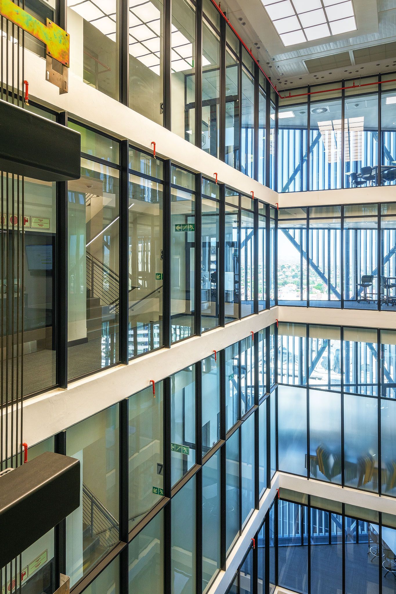 Interior atrium of modern office building featuring multi-level glass walls and steel structural elements.
