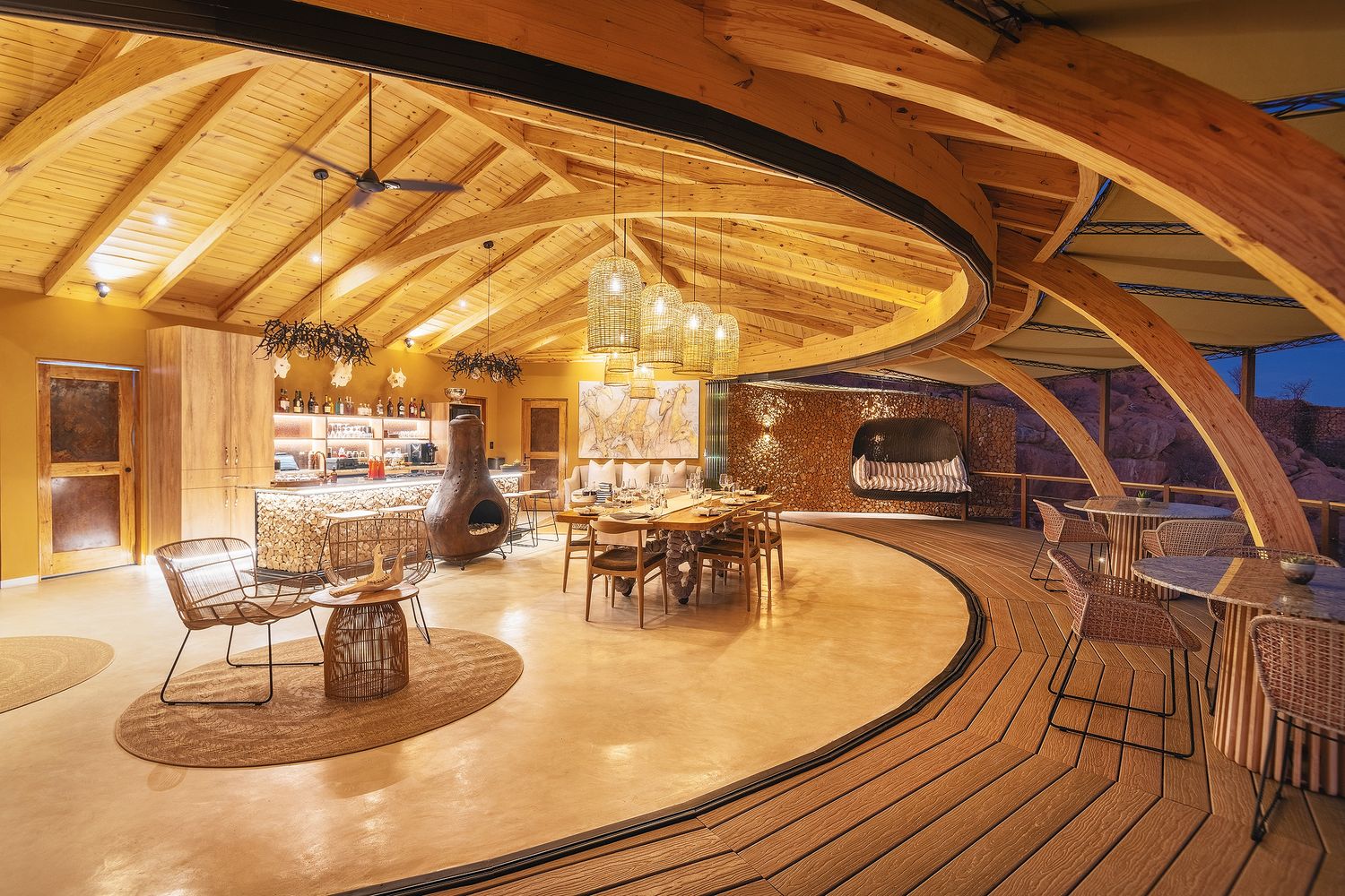 Luxury safari lodge interior with curved wooden architecture, warm lighting, and elegant dining area.