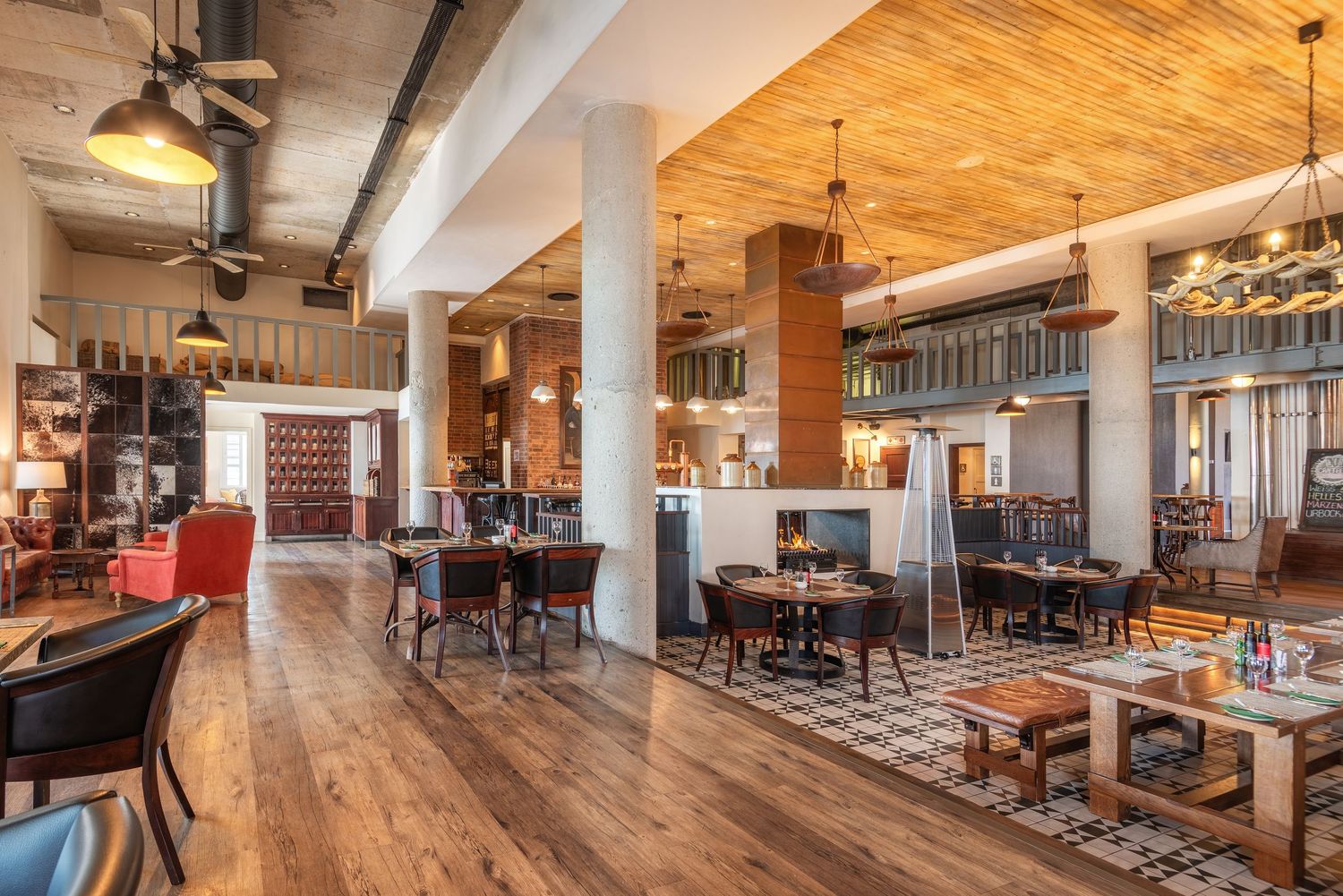 Rustic restaurant interior with hardwood floors, wooden ceiling, eclectic seating, and warm ambient lighting.
