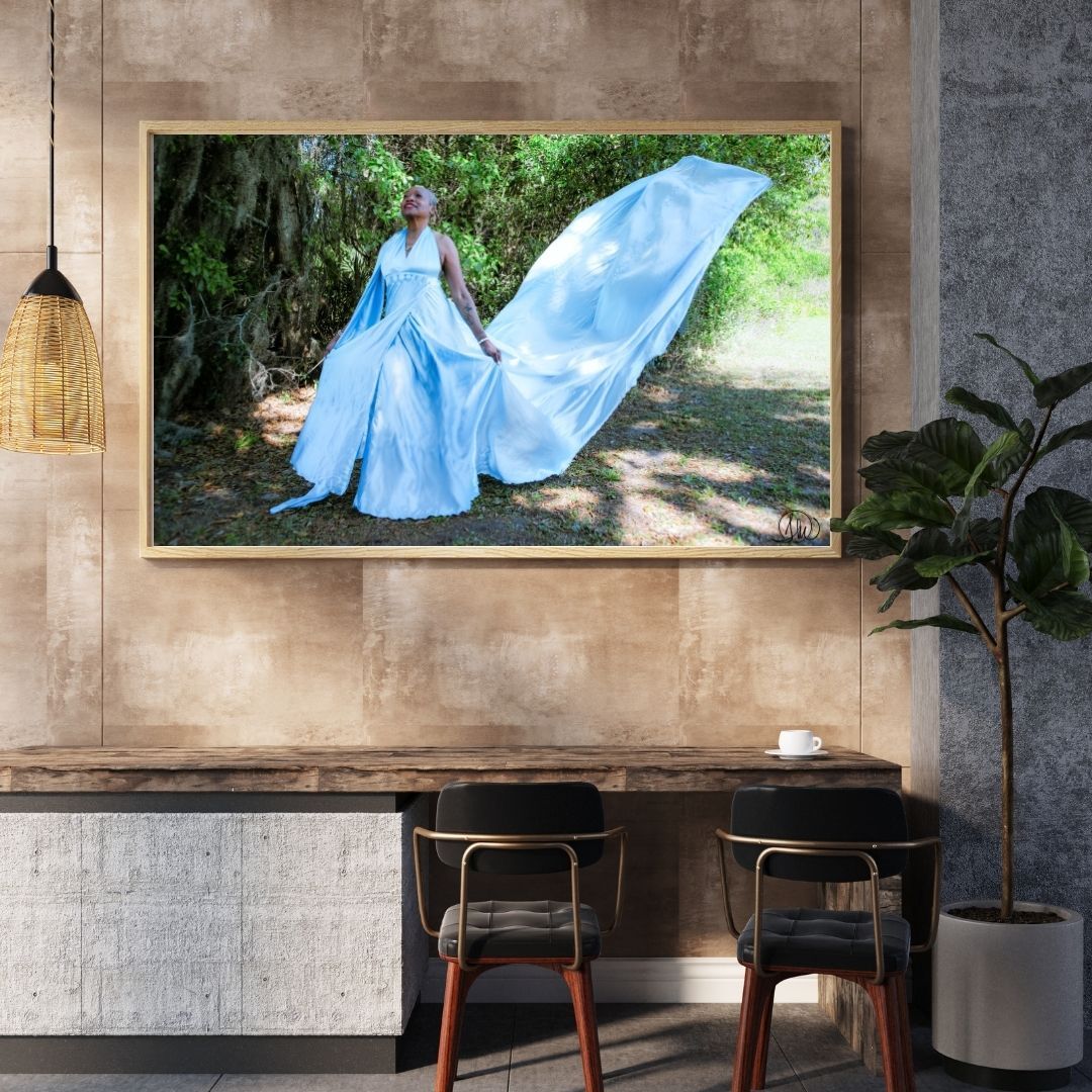 Framed wall art of a woman in a flowing blue gown displayed in a rustic cafe with wooden furniture.