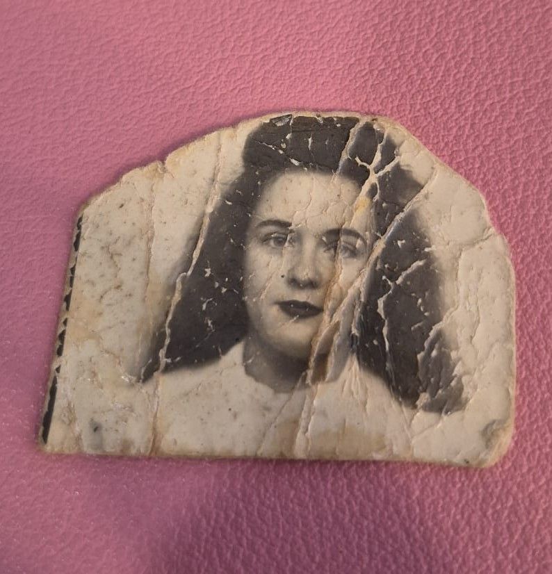 Severely cracked and damaged vintage photograph of a woman from the 1940s before photo restoration.