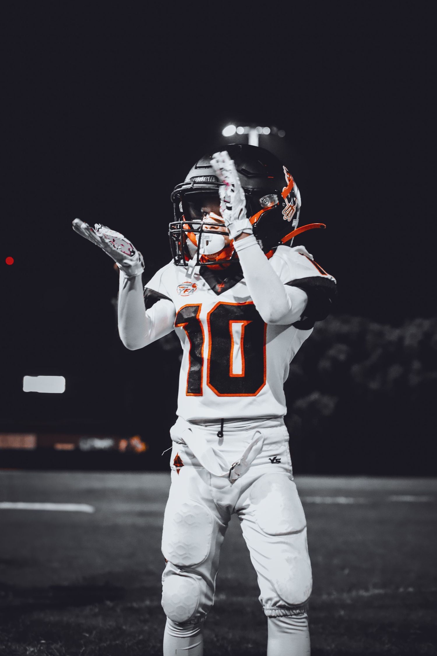 Young male football player in white uniform clapping hands on field.