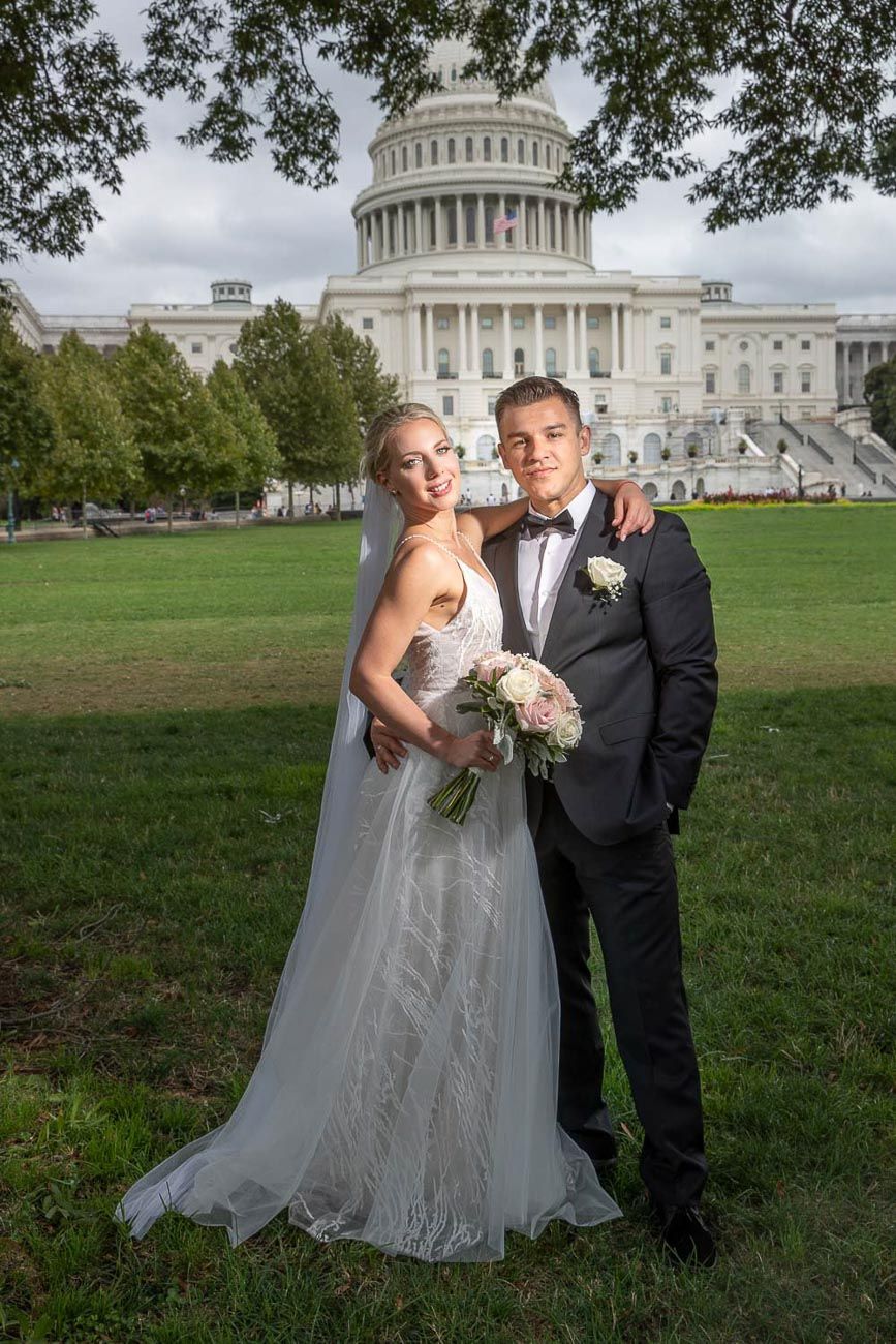 Bride and groom standing together on the lawn in front of the US Capitol building on their wedding day.