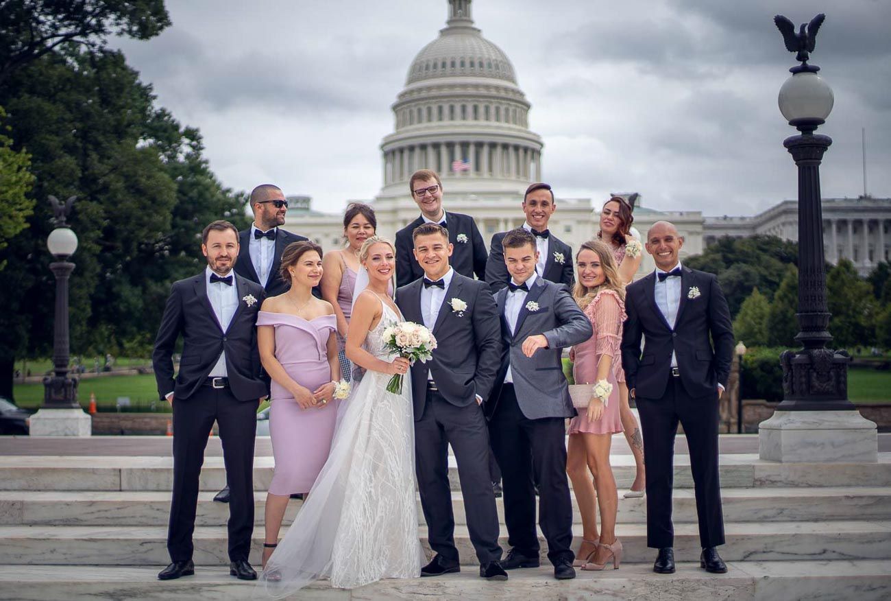 Bride and groom with wedding party in tuxedos and formal dresses on US Capitol steps in DC.