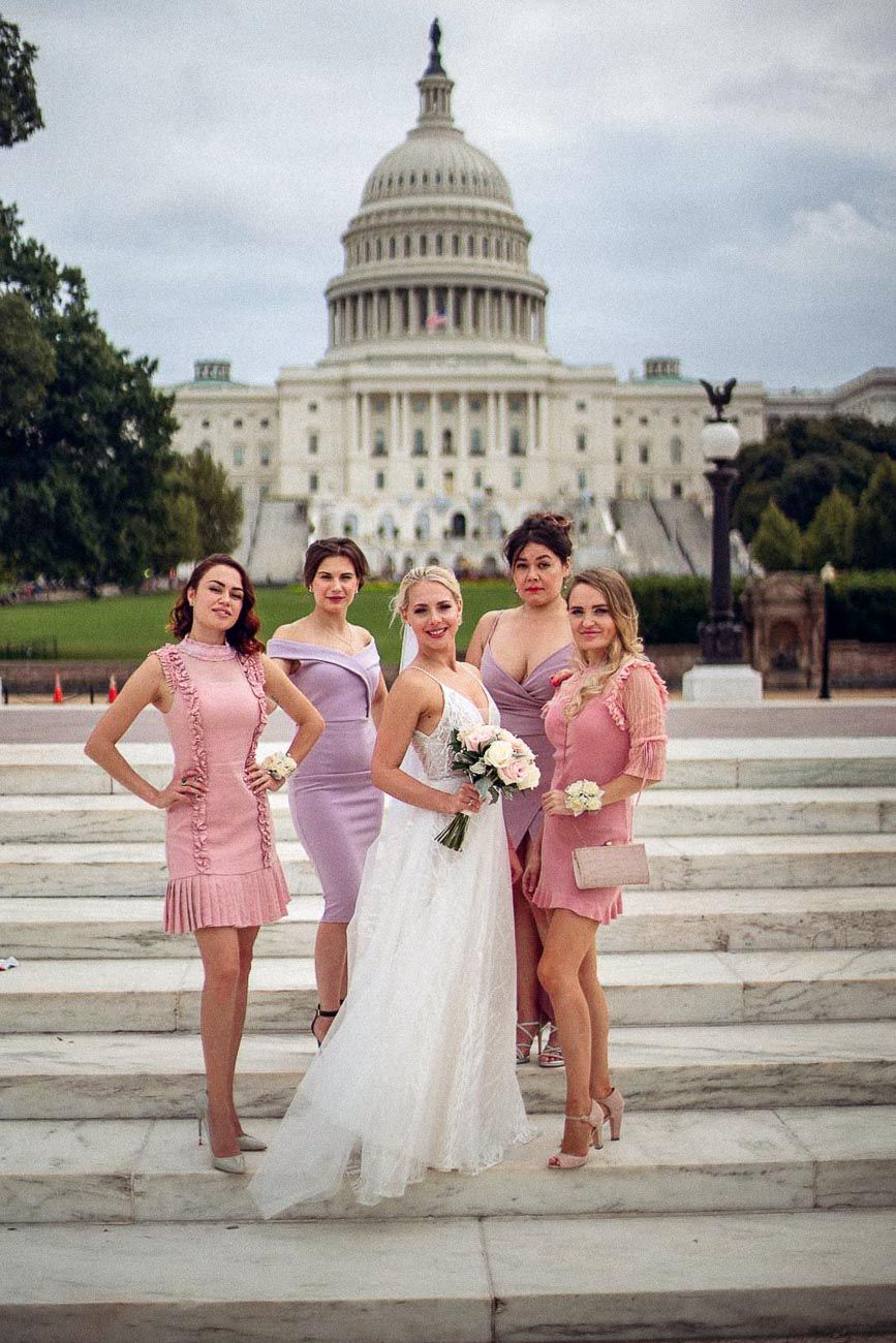 Bride with four bridesmaids in pink dresses posing on steps in front of the US Capitol building.