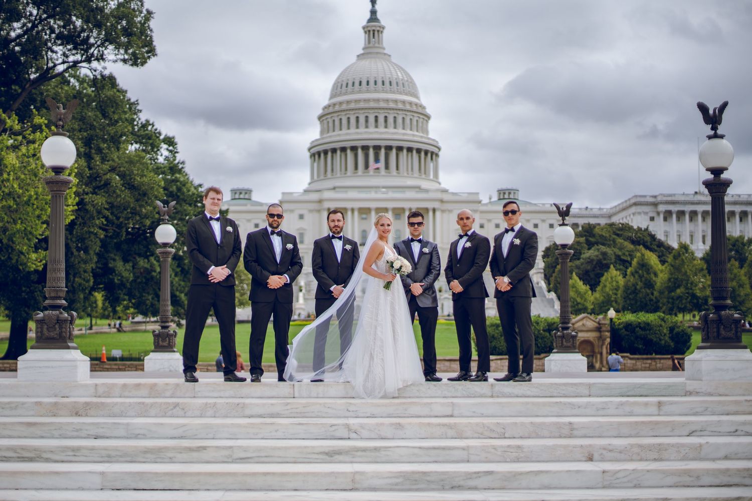 Wedding party poses on steps of US Capitol building in Washington DC with bride in white gown.