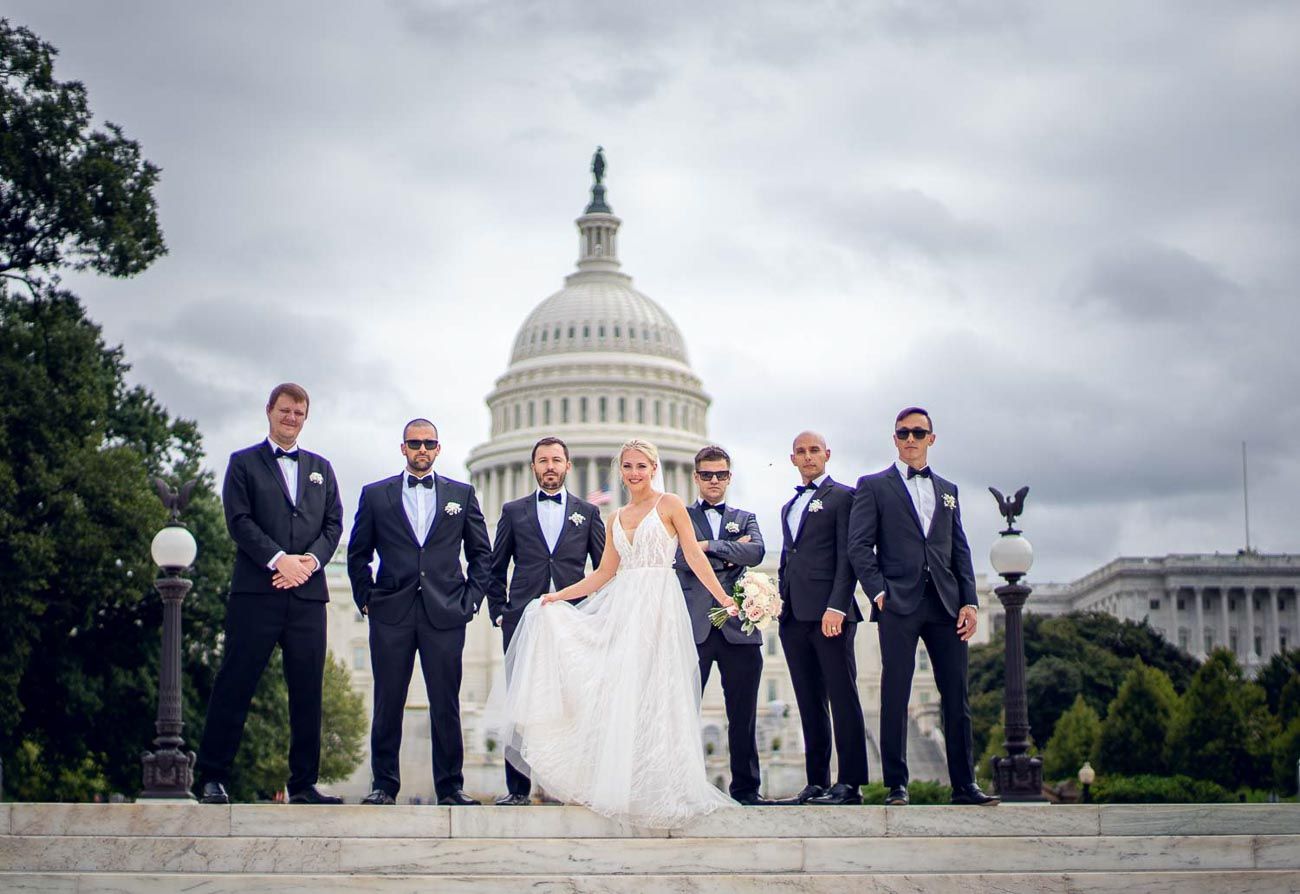Elegant wedding party poses before US Capitol Building on overcast day in Washington DC.