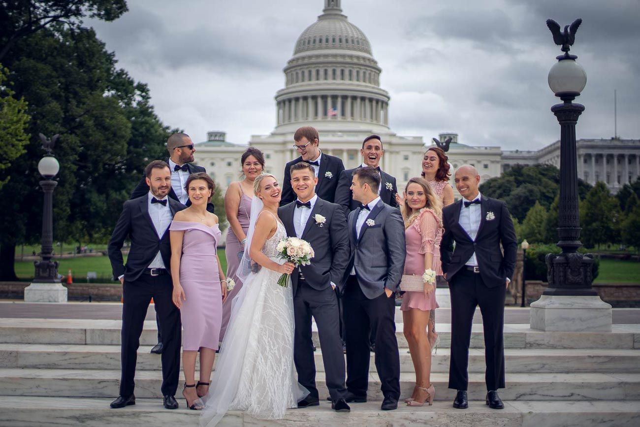 Wedding party in formal attire posing together on the steps of the US Capitol in Washington DC.