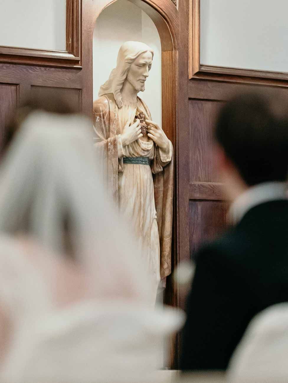 A religious statue of Jesus Christ displayed in a wooden niche during a Catholic wedding ceremony.