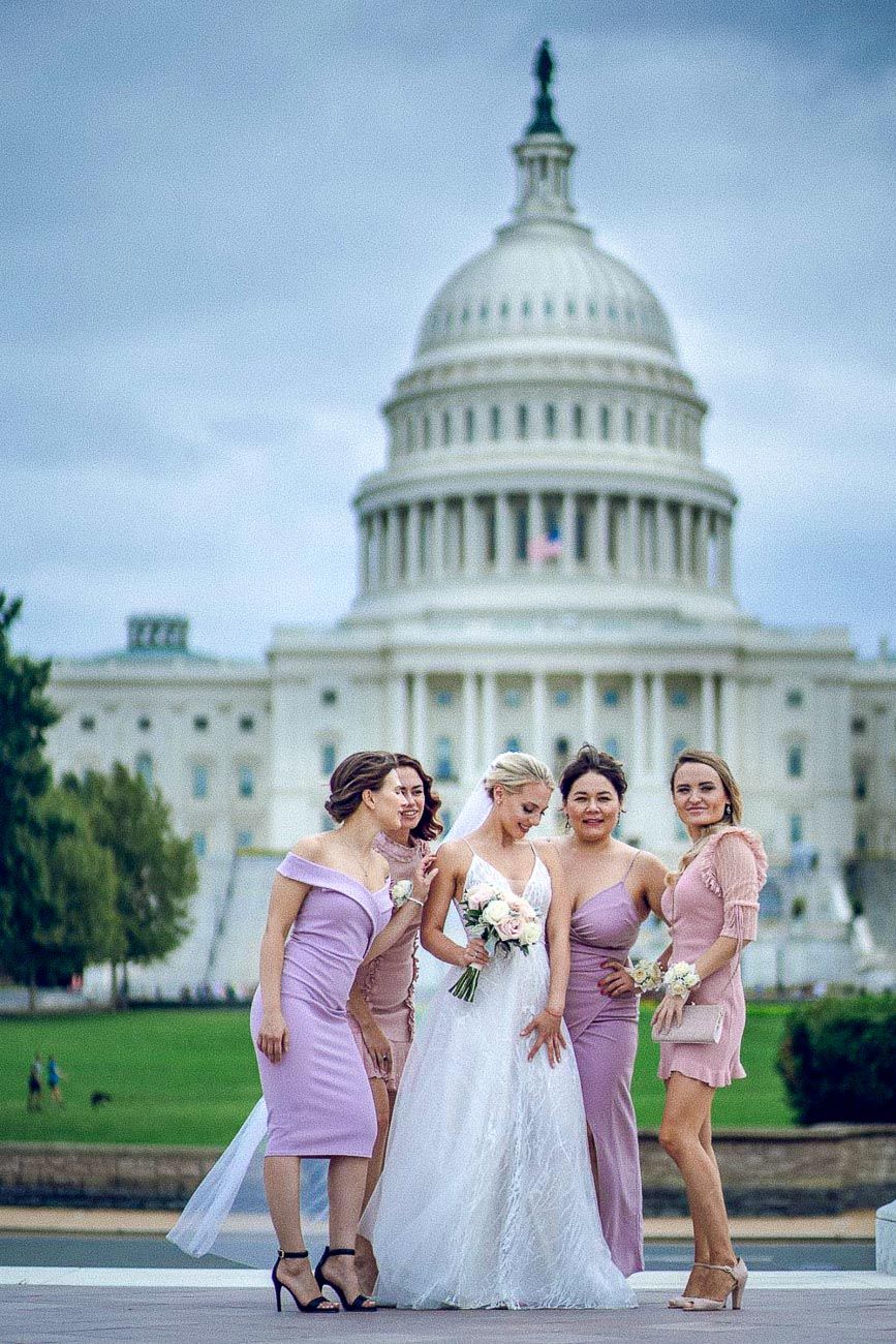 Bride with bridesmaids in lavender dresses posing in front of the US Capitol building in Washington DC.