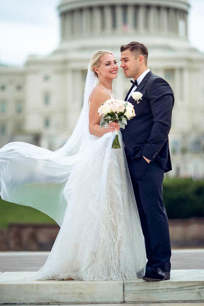 Wedding couple sharing a romantic moment in front of the US Capitol, bride's veil blowing in the wind.