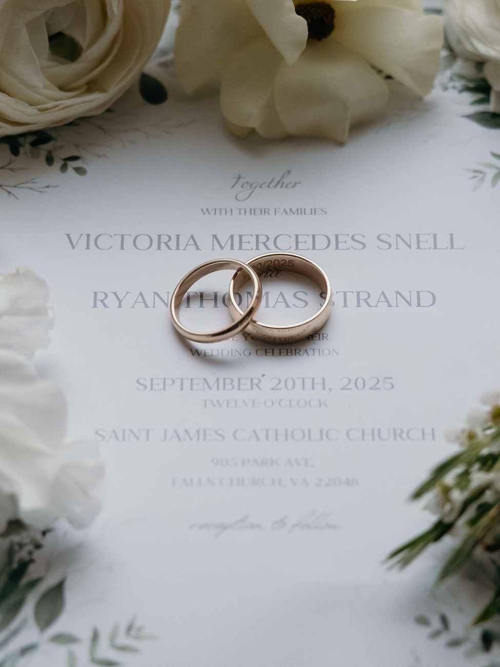 Wedding invitation for Victoria Mercedes Snell and Ryan Thomas Strand with gold rings on top.