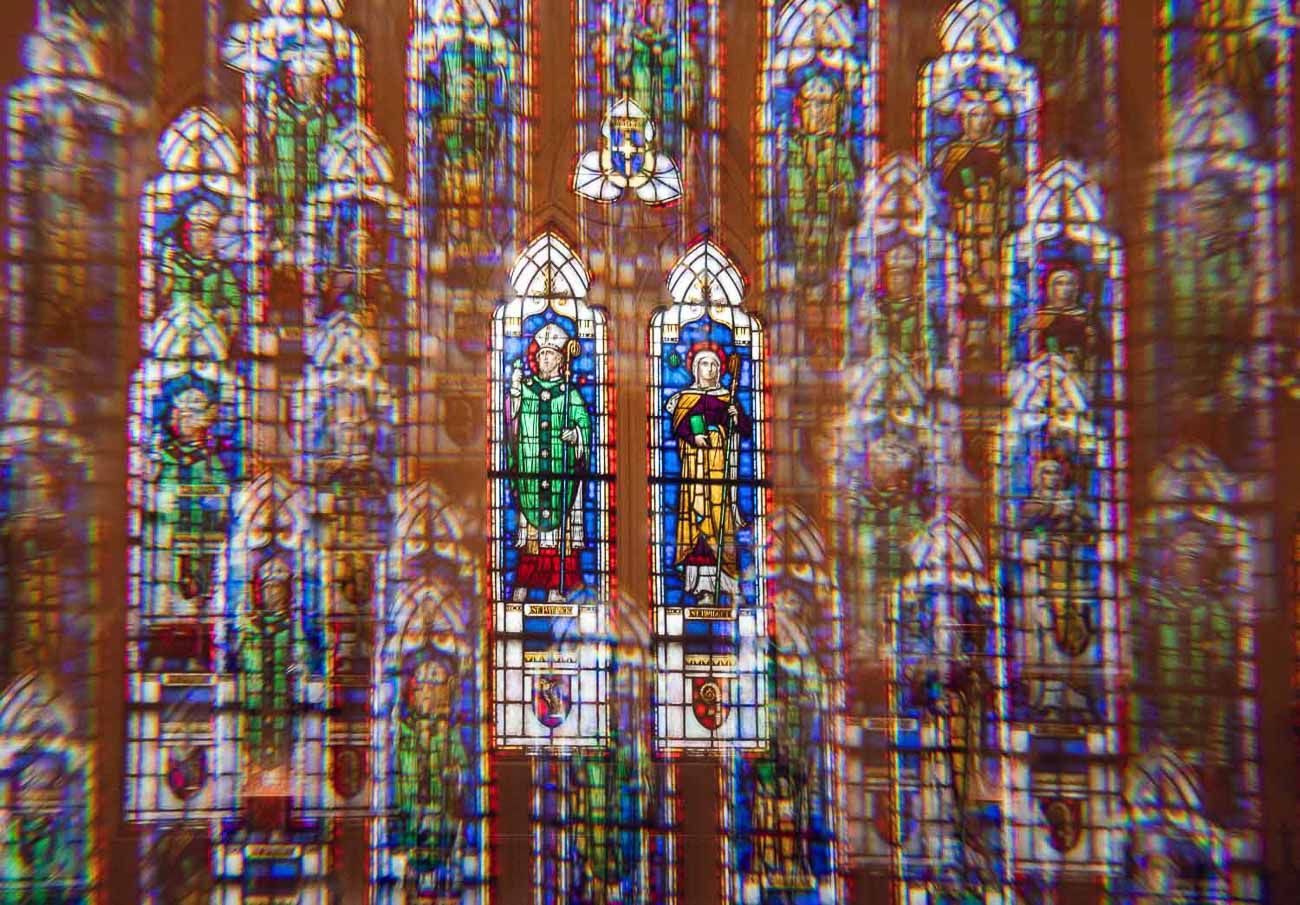 Stunning colorful stained glass windows inside a historic church with intricate religious figures.