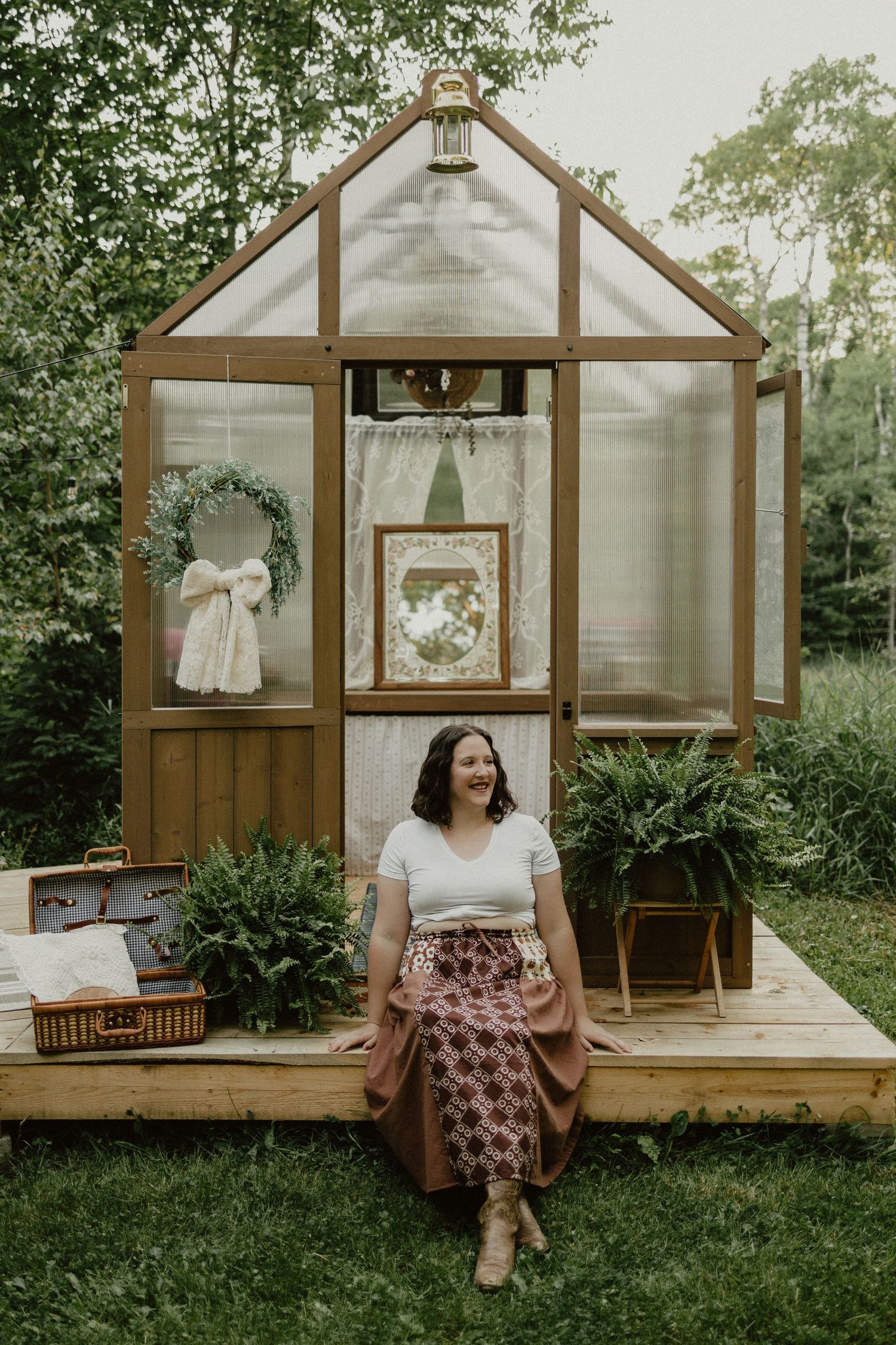 A sequence of photos showing a small wooden outdoor greenhouse with glass panels set in a backyard garden space.