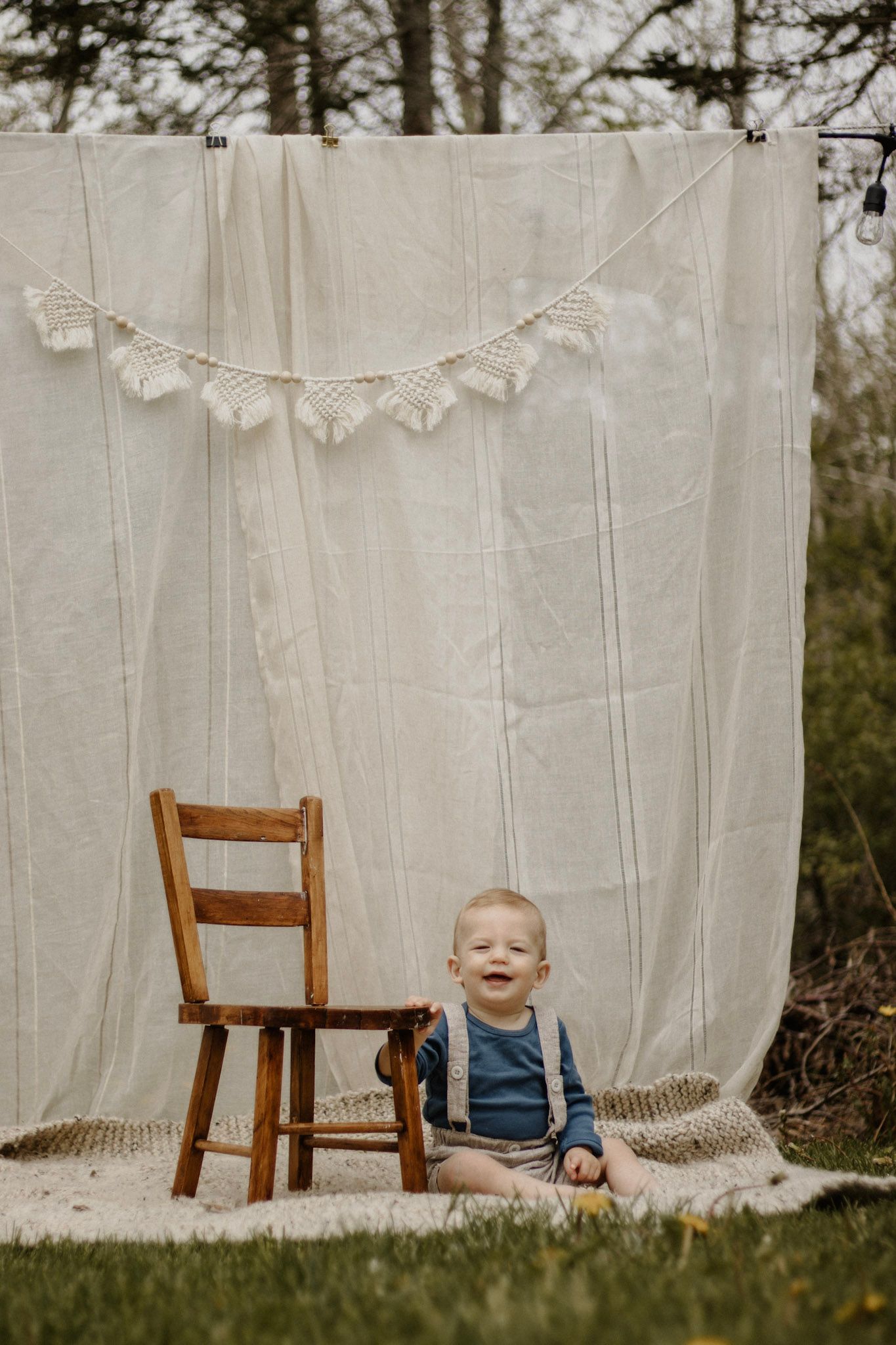 White fabric backdrop with lace bunting and wooden chair set up for outdoor photography.