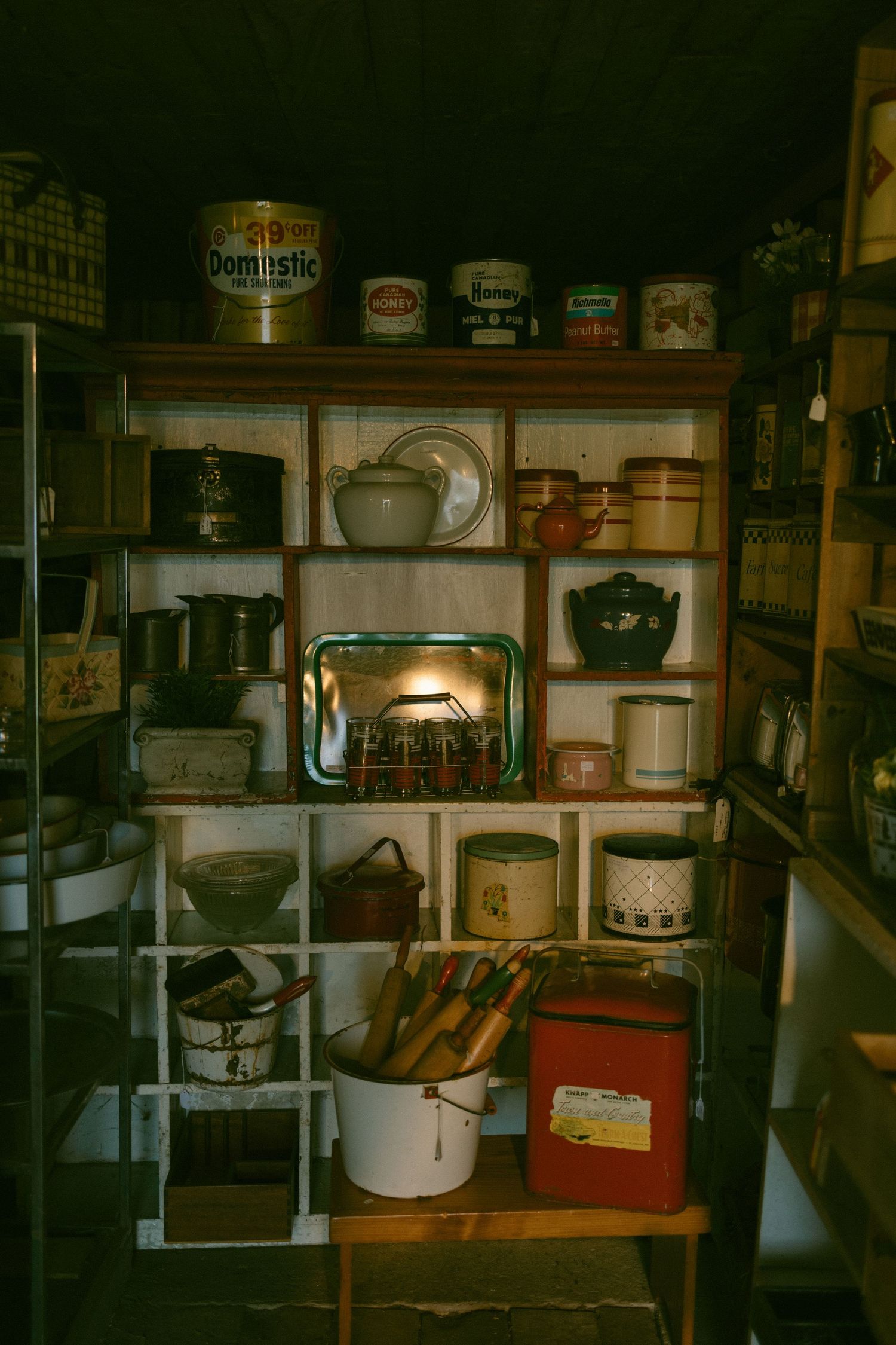 Vintage basement or cellar storage room with old containers, tins, and household items on wooden shelves.