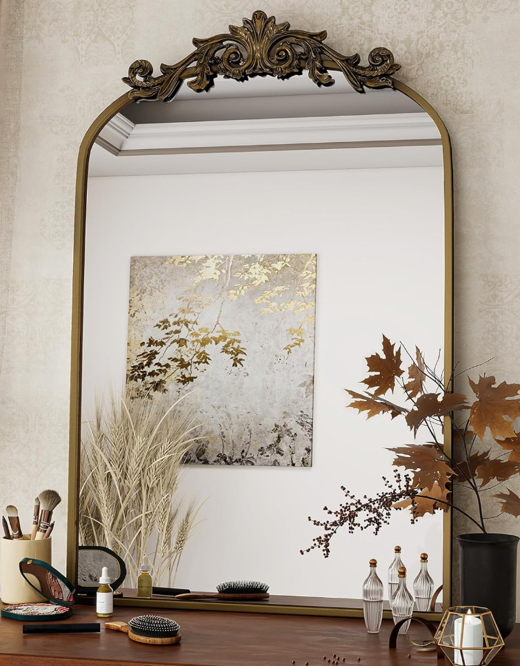 Elegant wall gallery with gold-framed mirrors and artwork displayed above a wooden console with fall decorative elements.