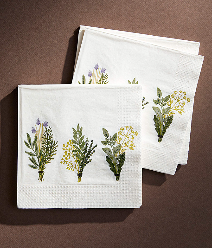 White paper napkins decorated with delicate watercolor floral and botanical designs in soft green and purple hues.