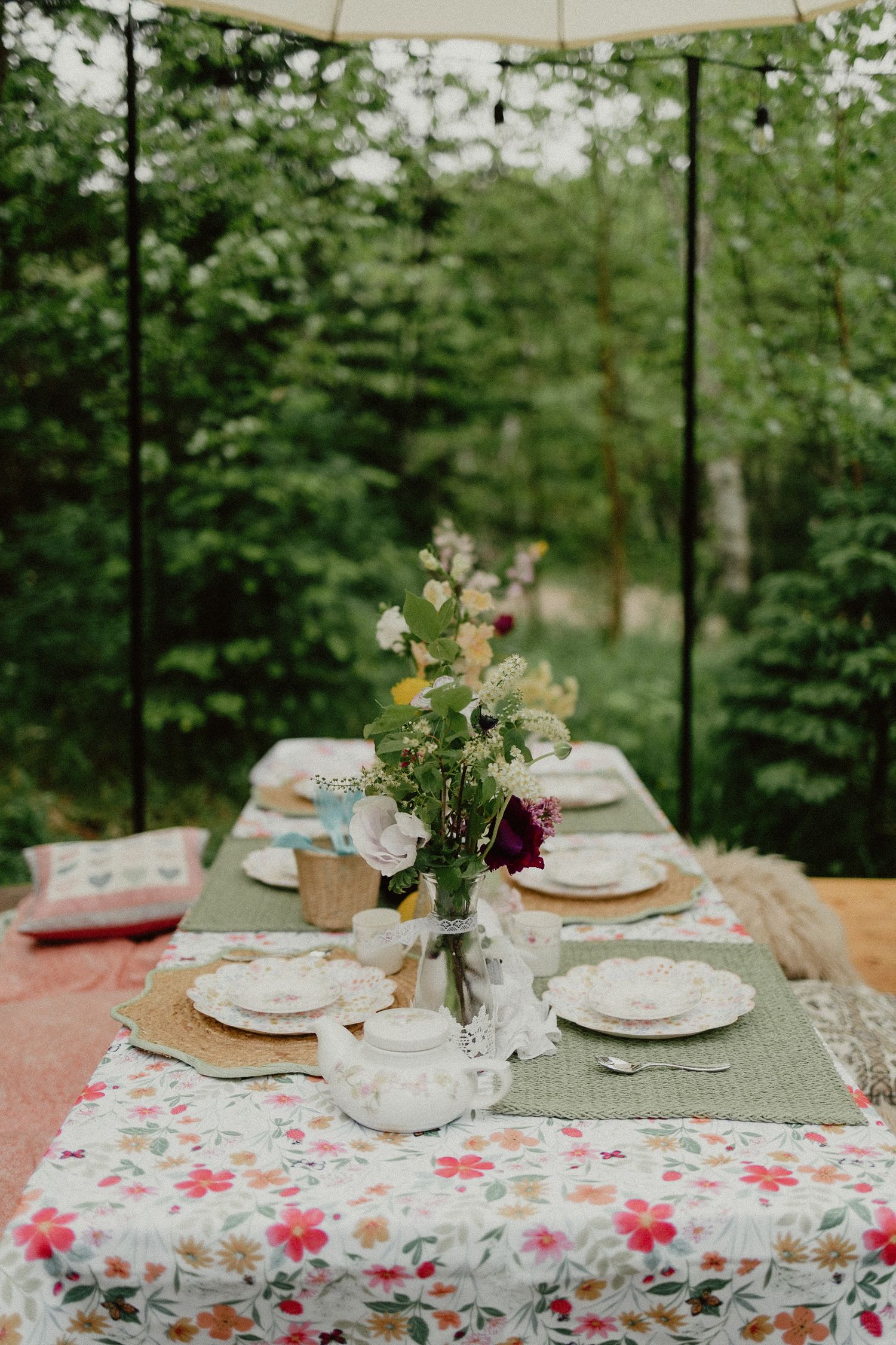 A charming garden table setting with floral tablecloth, neutral plates, and delicate flower centerpieces.