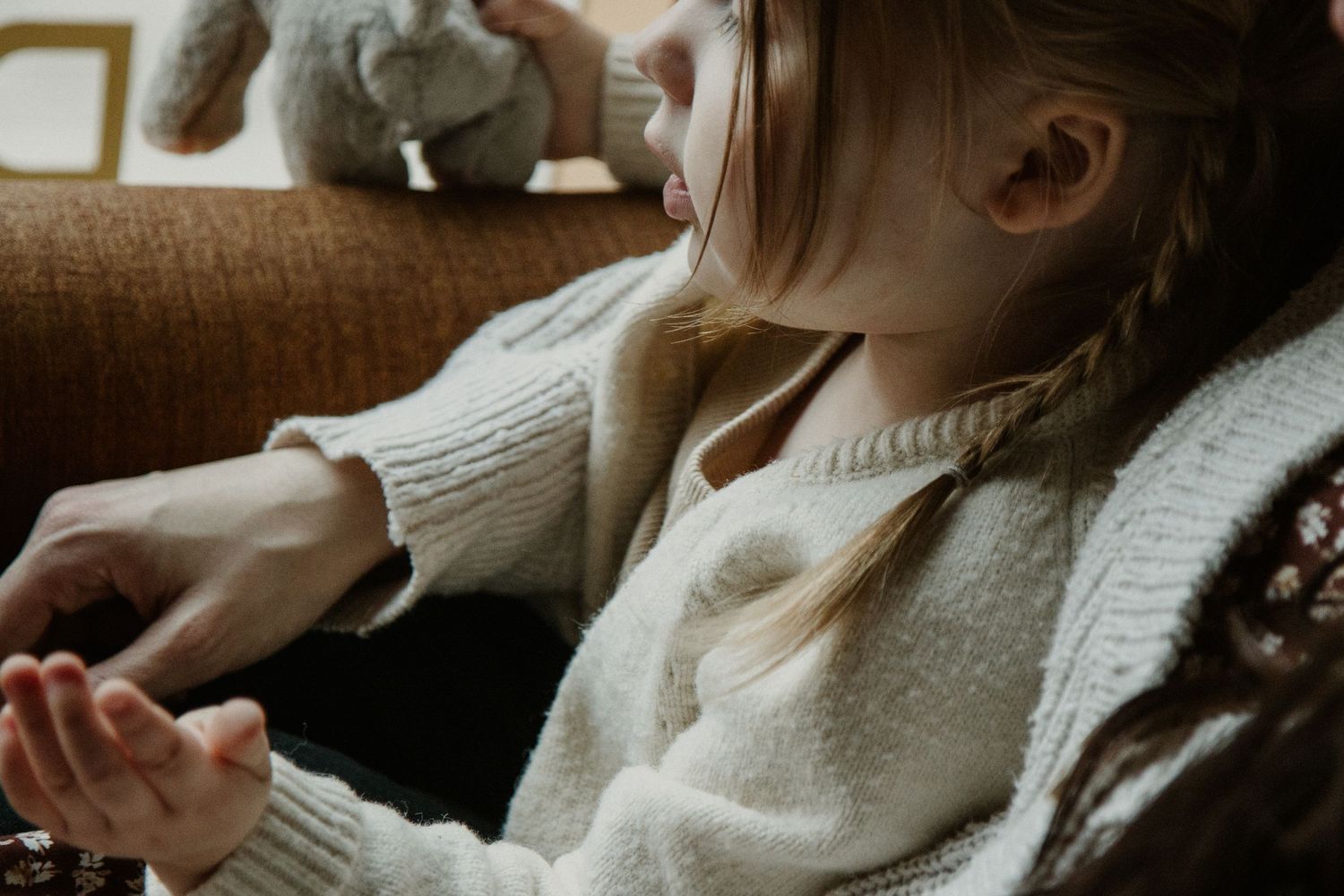 Person in white sweater relaxing on couch with soft natural lighting.