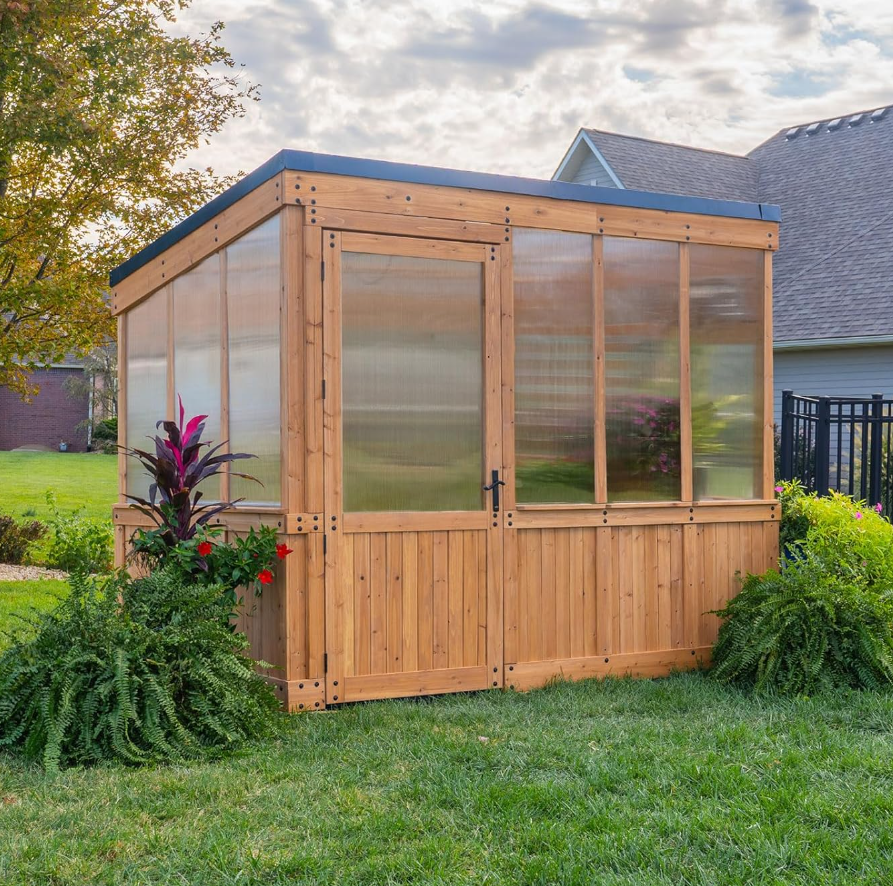 Five wooden windbreak panels with glass inserts are arranged on green grass lawn with cloudy sky overhead.