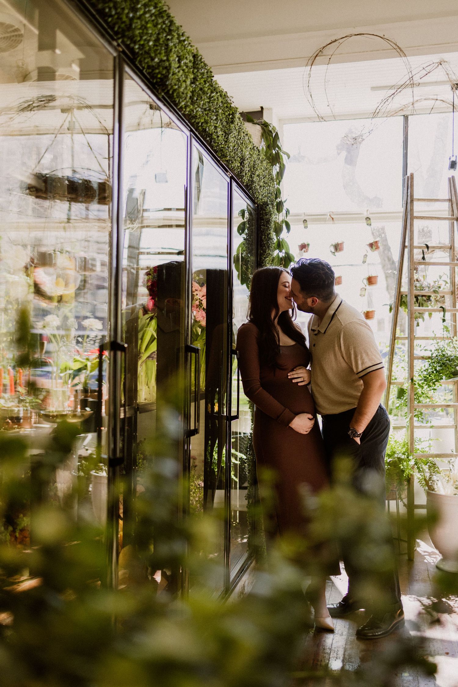 Intimate greenhouse moment surrounded by lush plants and glass reflections.