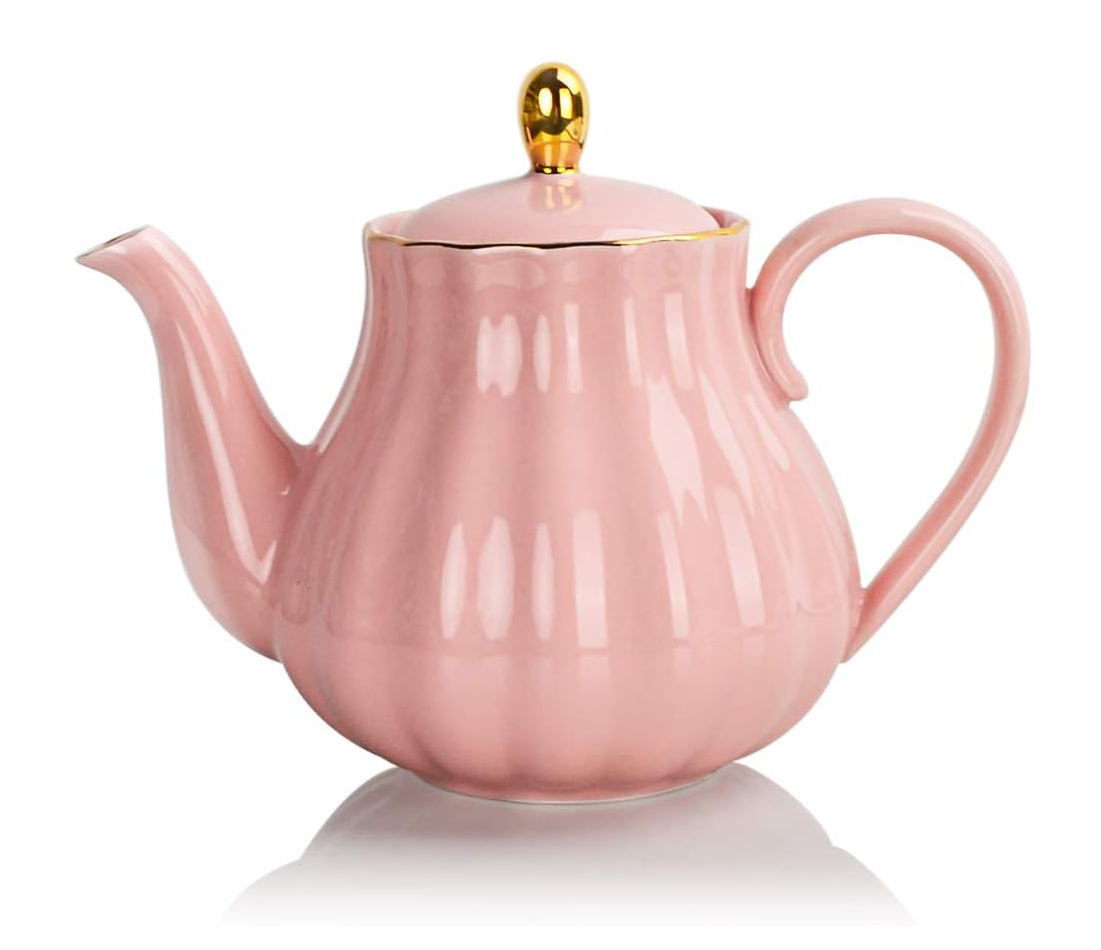 Four vintage-style pink ceramic teapots arranged in a row showing different sizes and designs with fluted details.