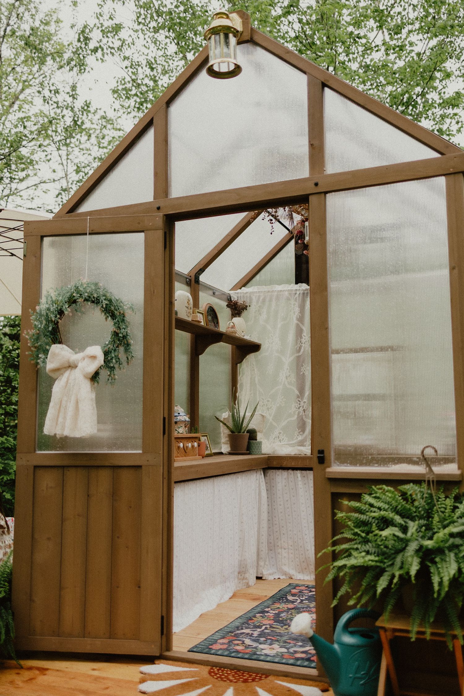 A sequence of photos showing the assembly process of a wooden greenhouse frame with translucent panels and plants inside.