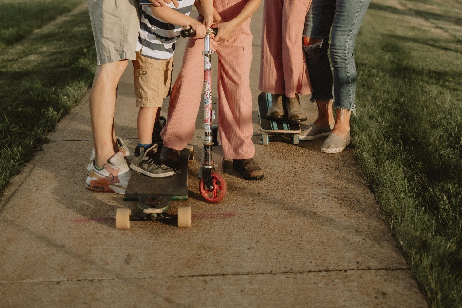 Close-up of feet and skateboards on concrete path showing casual summer attire.