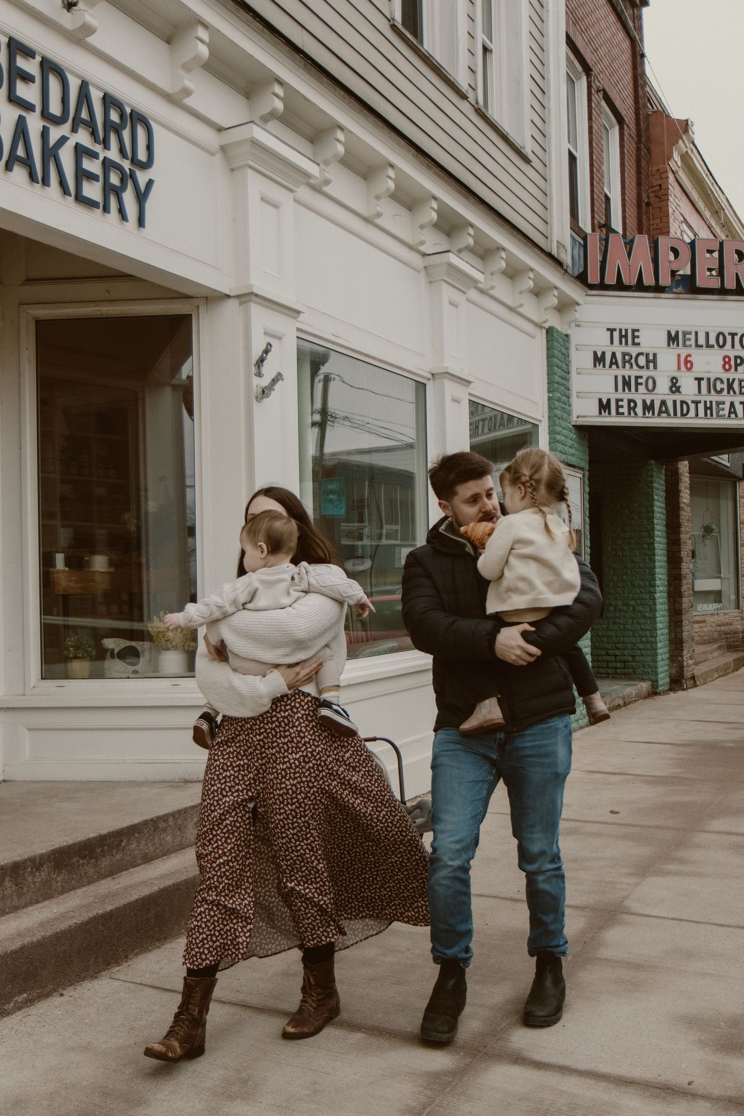 Family walking together outside bakery storefront in vintage-style setting.