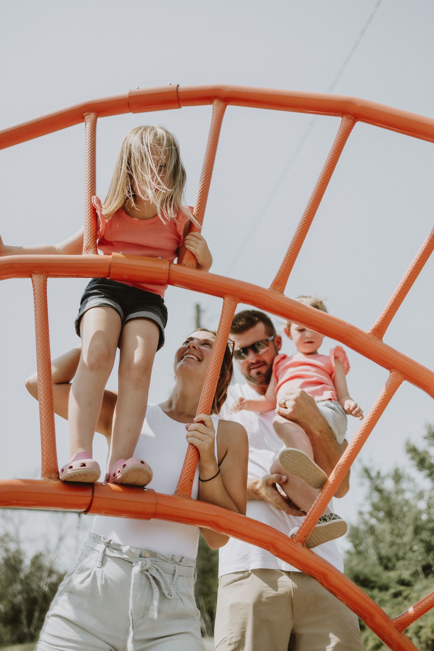 Family playing on the monkey bars at the park during a family photoshoot