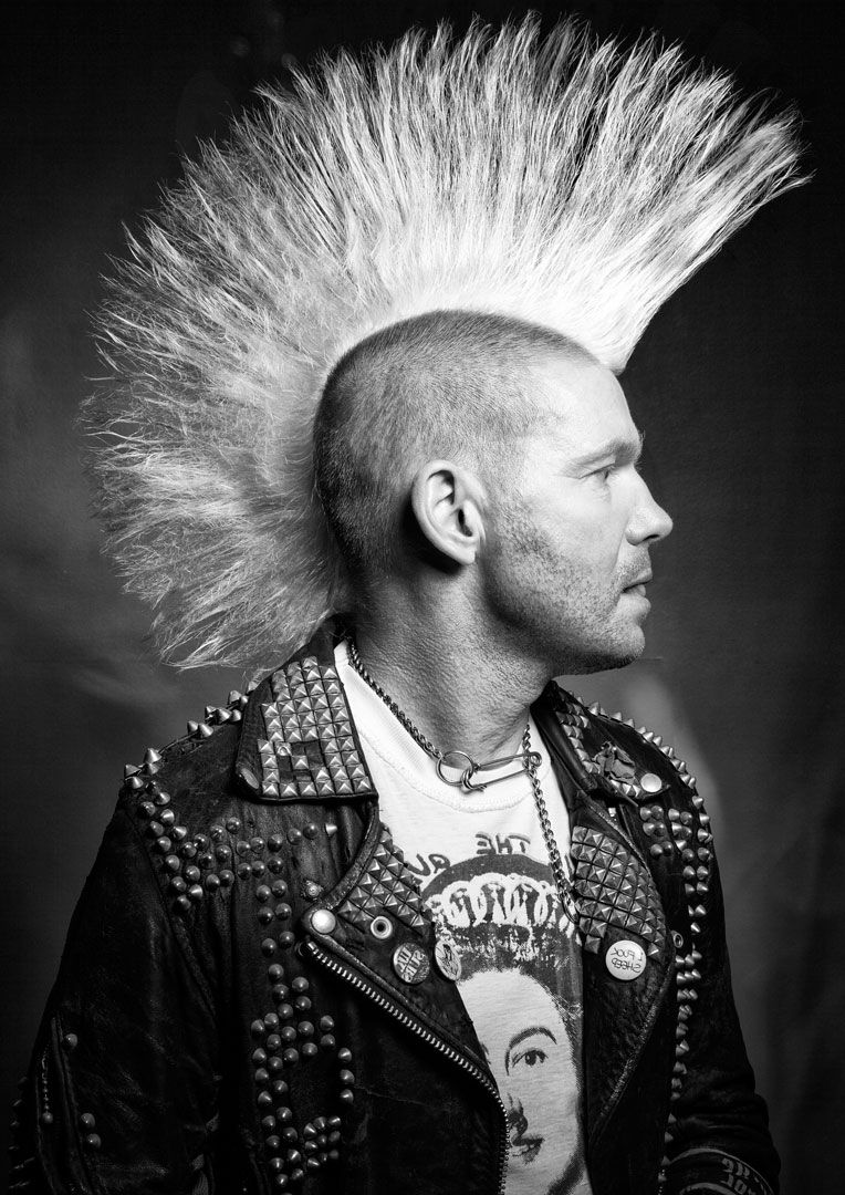 Black and white side profile of a person with a mohawk and feathered headdress, photographer Alec Watson