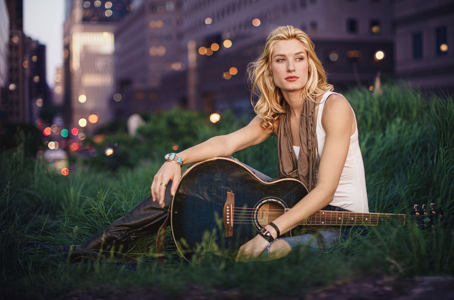 Woman with blonde hair sitting on a step outdoors in an urban setting at dusk, Courtney Graf, photographer Alec Watson