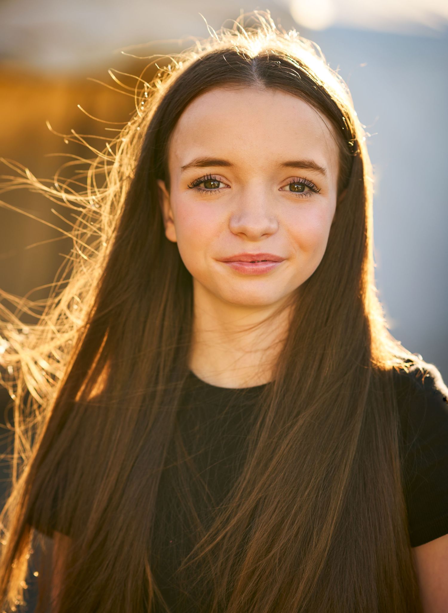 Portrait of a young woman with long brown hair, smiling at the camera
Grace, headshot, photographer Alec Watson