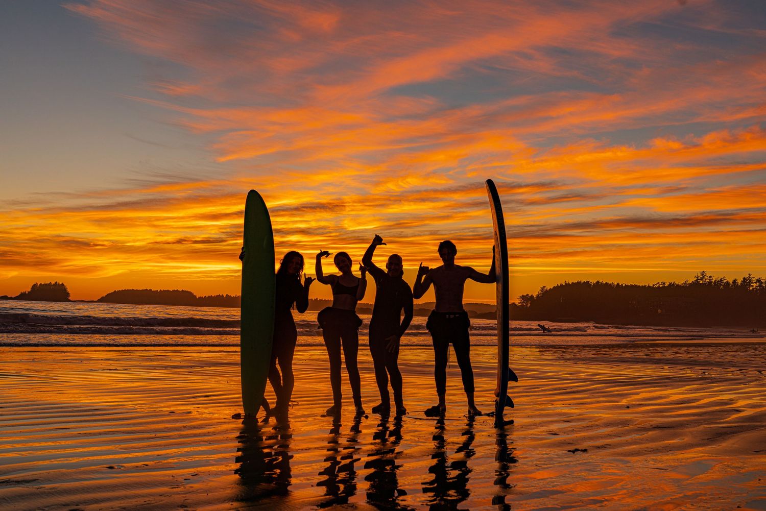 Silhouettes of surfers carrying surfboards along the beach at sunset, photographer Alec Watson