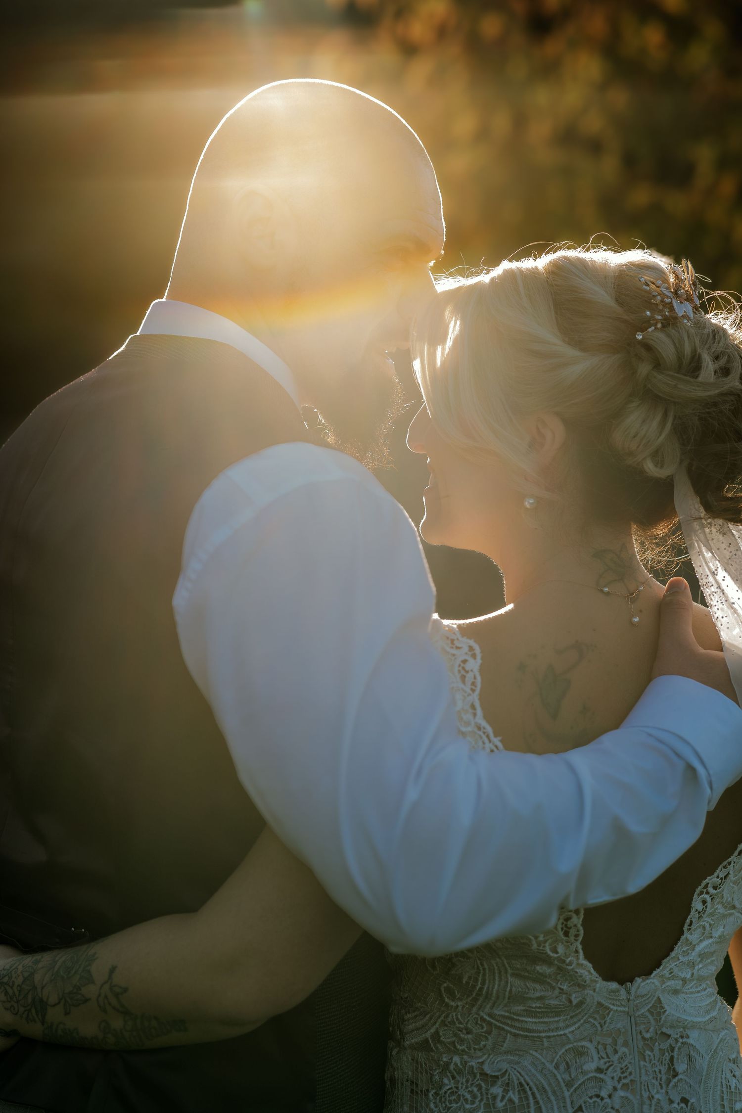 Silhouetted couple embracing in warm sunset light creating a romantic backlit effect.