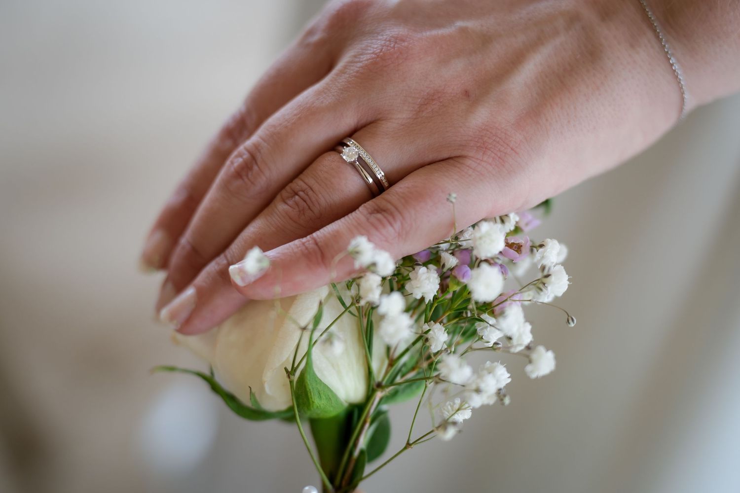 Delicate hands arrange white flowers and greenery in an artistic wedding detail shot.