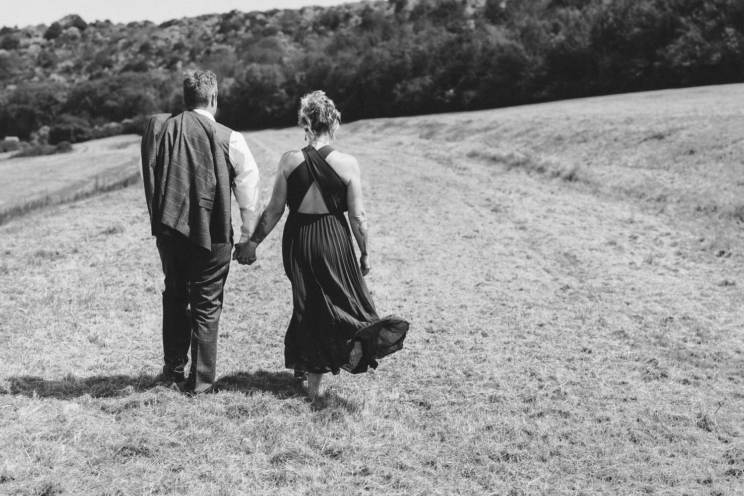 Wide landscape shots of couple walking together on rolling hills.
