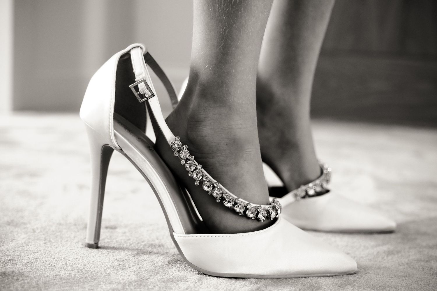 Black and white detail of elegant bridal shoes and accessories.
