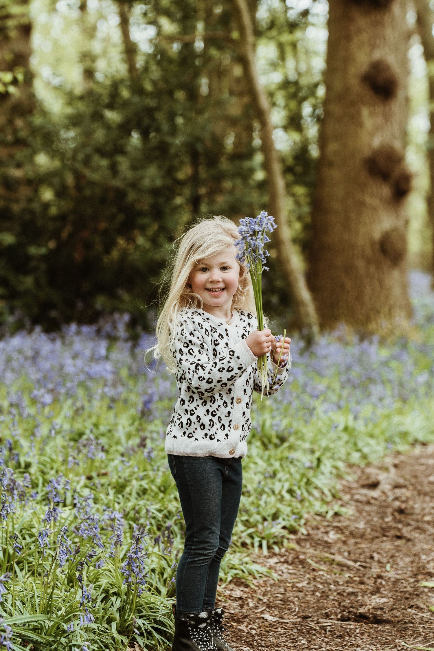 Child exploring a magical bluebell forest while wearing a floral print top.
