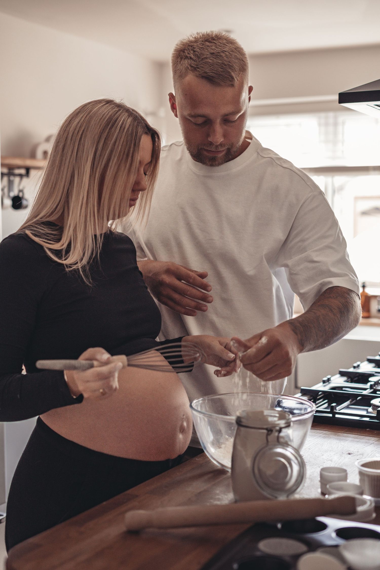 A couple prepares something together in their bright modern kitchen.