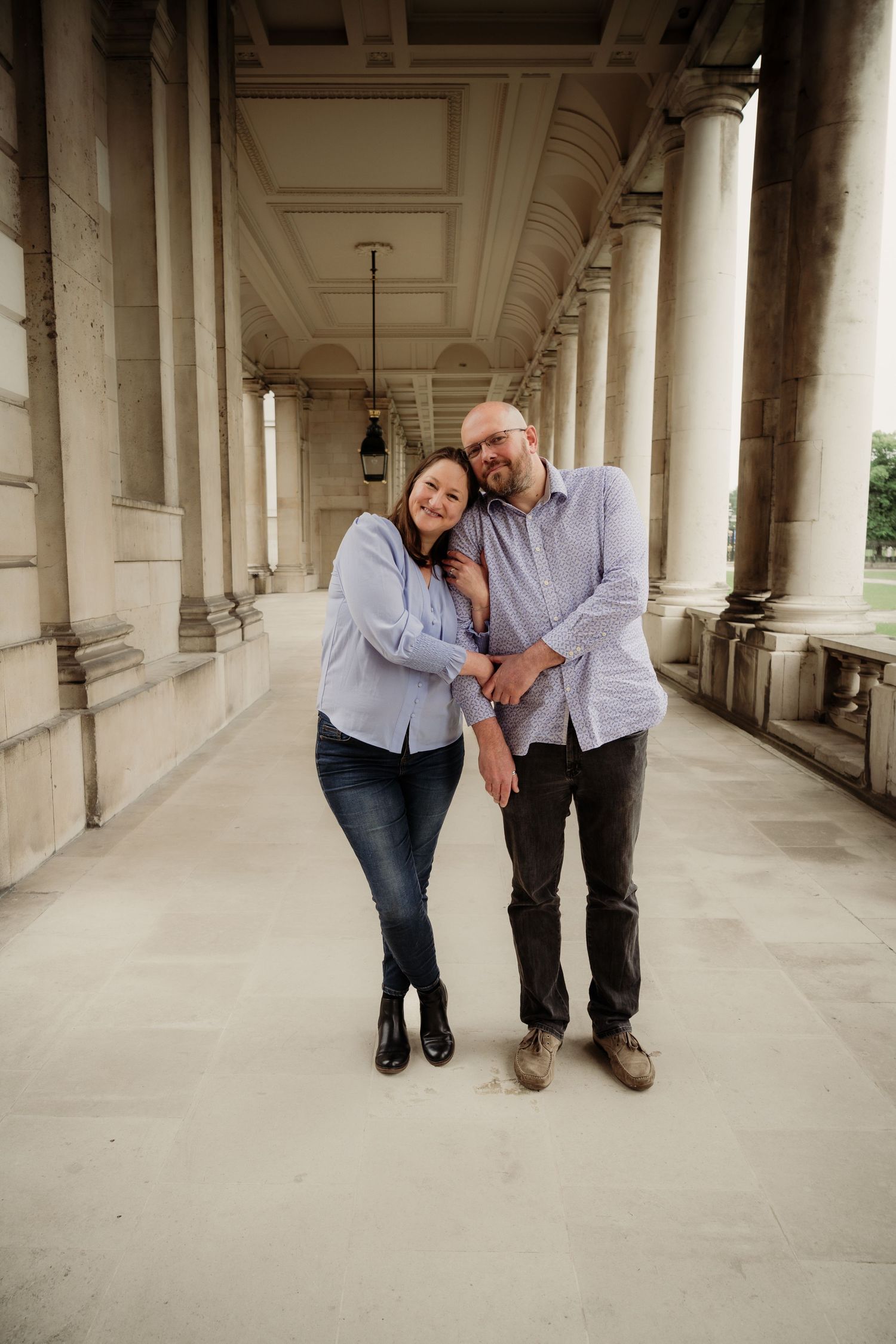 Couple sharing intimate moments in a historic colonnade setting.