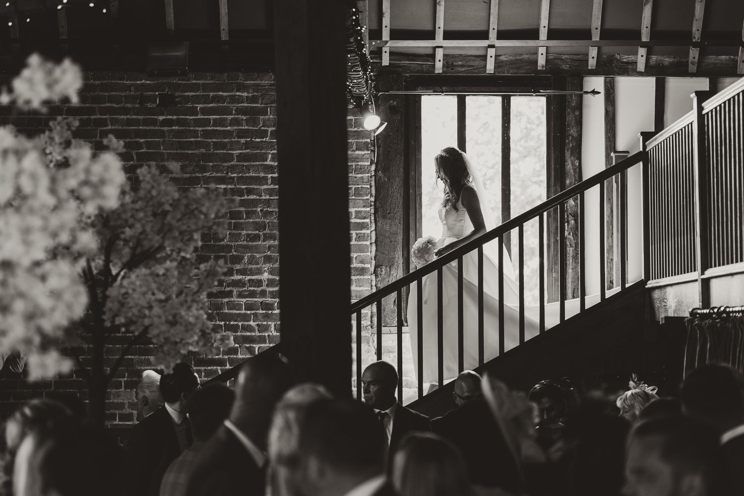 Dramatic black and white staircase sequence with brick walls and iron railings.
