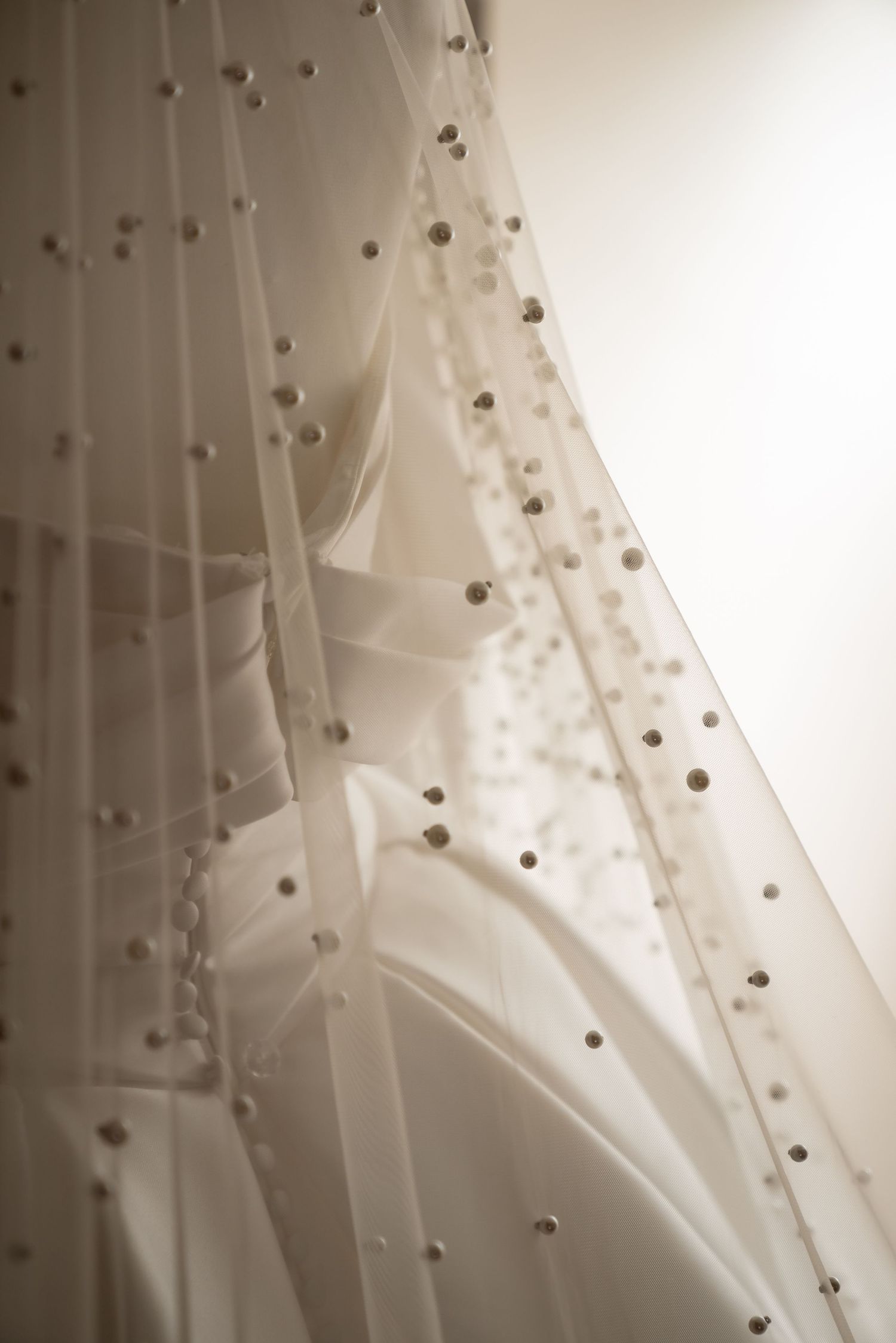 Close-up detail of delicate beaded wedding veil with scattered pearl embellishments.