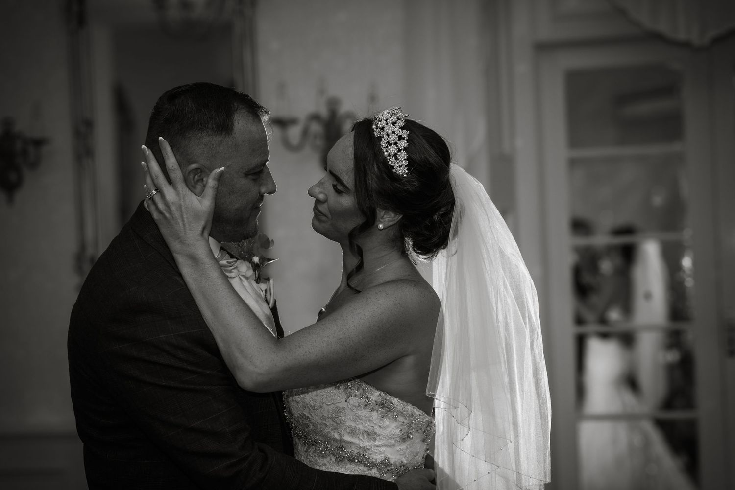 Black and white romantic moment captured in an elegant indoor setting.